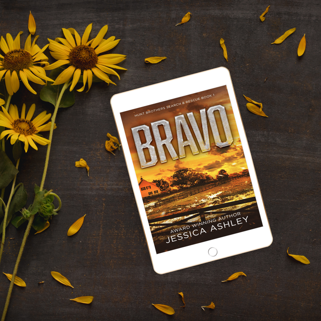 Tablet displaying the book 'Bravo' by Jessica Ashley with sunflowers on a dark surface