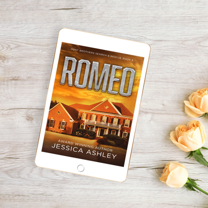 Tablet displaying the book cover of 'Romeo' by Jessica Ashley on a wooden surface with flowers.