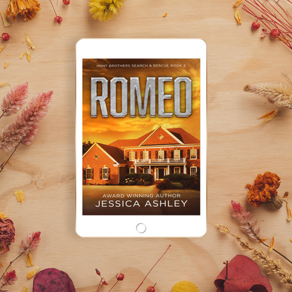 Tablet displaying the book cover of 'Romeo' by Jessica Ashley on a wooden surface with dried flowers.